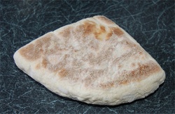 flat, triangular bread with pale surface irregularly covered with browning.