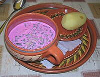 Borscht sprinkled with parsley, served with a dollop of sour cream and a slice of rye bread