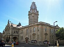 Stone building with colonnaded entrance. Above is a clock tower.