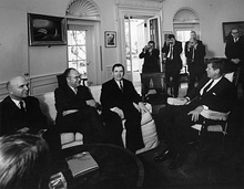 Picture of men wearing suits in a meeting.