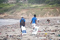 A man and woman dragging a bag of plastic waste collected from the beach in Ghana