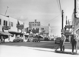 Left: Looking easterly down Second Avenue from Cushman Street in 1955.  In the background is the Polaris Building, the tallest building in Fairbanks since its completion in 1952.  Right: The Polaris Building in May 2011, over a decade after being abandoned.  The awning of its last occupant, the defunct Anchorage-based Northern Lights Hotel chain, is still visible.