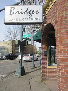 Photograph of a sign and lamp post outside a restaurant at a street intersection