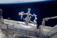 Commander Volkov stands on Pirs with his back to the Soyuz whilst operating the manualStrela crane (which is holding photographer Oleg Kononenko).