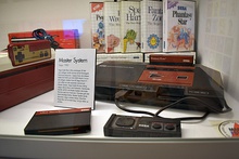 A video game console with numerous video game boxes behind it.