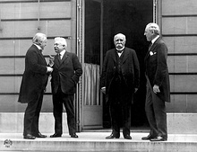 Four men with suits outdoors talking.