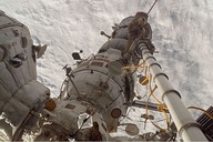 Commander Volkov stands on Pirs with his back to the Soyuz whilst operating the manualStrela crane (which is holding photographer Oleg Kononenko).