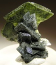 Green titanite crystal perched right at the top of a column of gray, chlorite-included crystals