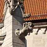 Gargoyle representing a comical demon at the base of a pinnacle with two smaller gargoyles, Visby, Sweden