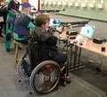 Para shooting with a rifle sitting in a wheelchair.