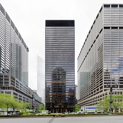 A tall glass tower, as viewed from across Park Avenue. There are two other buildings to the left and right.