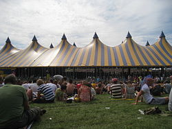 The Alpha is the largest stage at Lowlands festival, with a capacity of 15,000 attendees. It succeeded the "Hoofdpodium" (main stage) in 1993. The blue and yellow striped circus tent (on the left) was replaced in 2017 by a higher, more open tent with arched roof (on the right).[23]