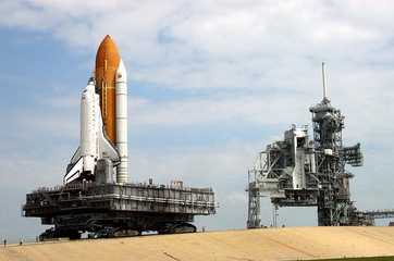 A crawler-transporter carrying Discovery (STS-114) travels the ramp to Launch Pad 39B. The vehicle's back end can be raised, keeping the Shuttle and the MLP level.