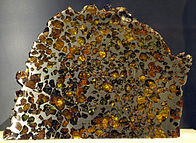 Polished slices of the stony-iron Esquel pallasite: at the Canadian Museum of Nature (left), at the American Museum of Natural History (middle) and encased yellow-green olivine crystals in the iron-nickel matrix are clearly visible (right).