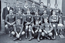 Three rows of rugby players wearing their playing uniforms and caps