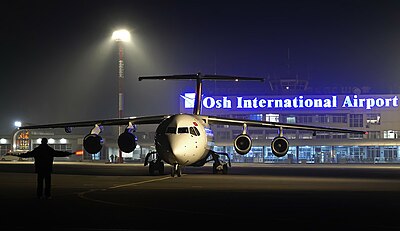 Airport terminal at night with TezJet aircraft taxing to stand.