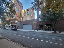 two one-story brick buildings next to a taller building all constructed of brick on a street lined with trees