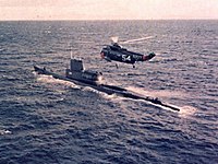 A helicopter hovering above a submarine