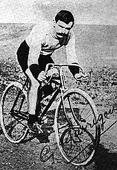 A signed postcard of a man on a bicycle on a sandy road.