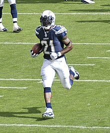 LaDainian Tomlinson carrying a football in a San Diego Chargers uniform and helmet.