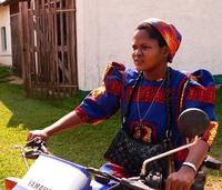 A sister of the Theresienne Sisters of Basankusu wearing a brightly coloured habit, riding a motor-bike, Democratic Republic of Congo, 2013[24]