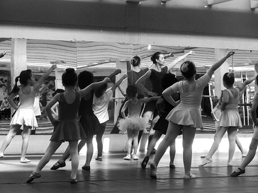 Ballet class of young girls wearing leotards and skirts in 2017