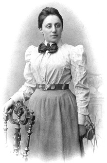 Portrait of Emmy Noether in her 20s with her hand resting on a chair