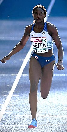 Black woman in a blue and white kit running on a track.