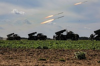 Military vehicles firing rockets in a field