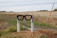 A sculpture consisting of two white posts holding a black spectacles frame in Buddy Holly's characteristic style