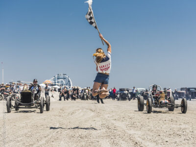 Woman jumping in air holding start flag for beach derby race in The Wildwoods NJ