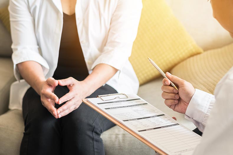 Photo of woman sitting while doctor reads information from a chart