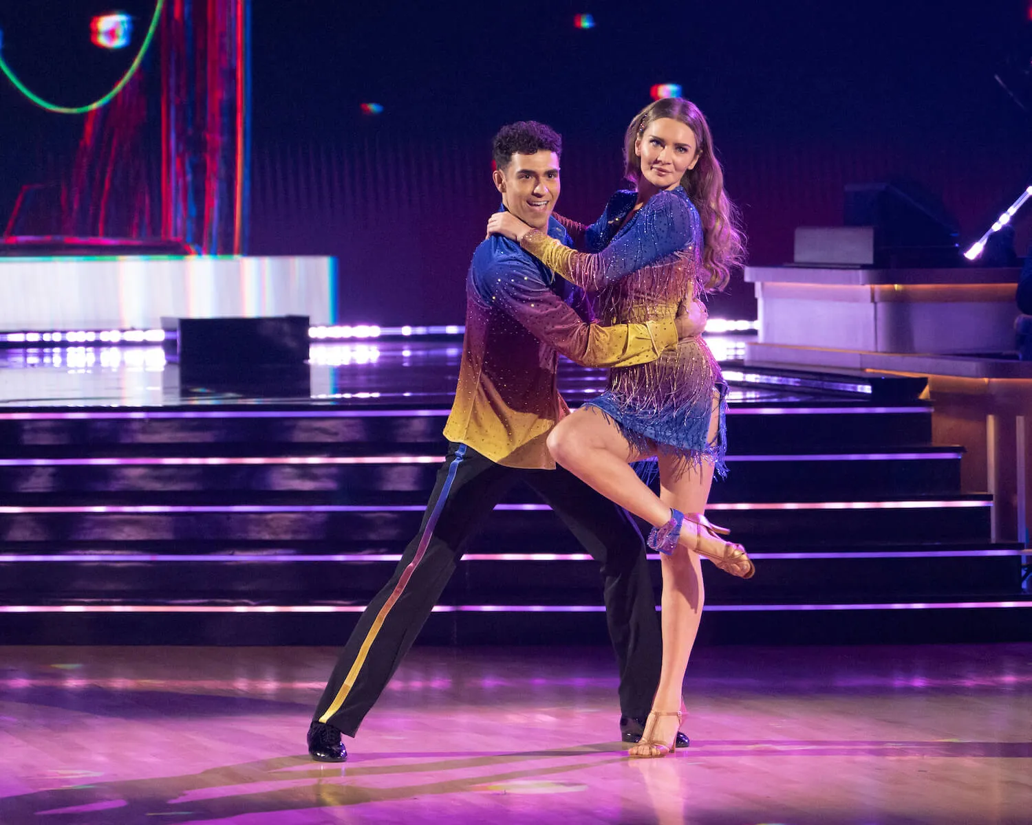 Anna Delvey dancing with Ezra Sosa on 'Dancing With the Stars' Season 33. Delvey has one leg bent and leaning on Sosa as her arms grip his shoulders. Sosa is supporting Delvey's waist.