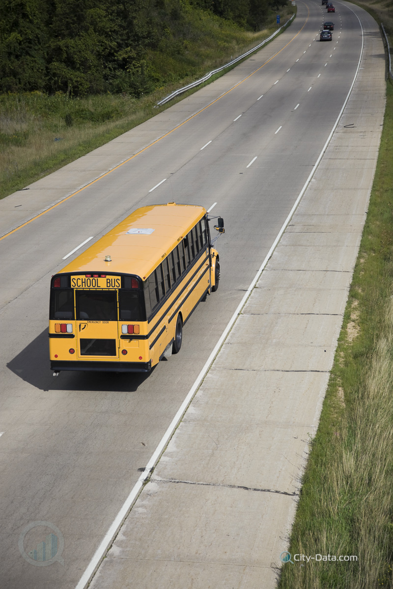 Yellow school bus seen from a bridge.