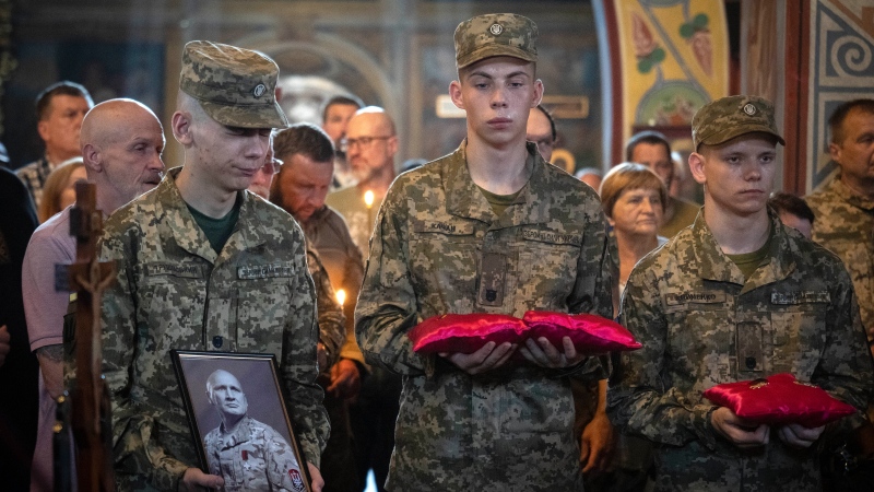 Young Ukrainian soldiers hold the portrait and awards of prominent right-wing activist and soldier Mykola Kokhanivsky during his funeral in Kyiv on July 16, 2024. (Efrem Lukatsky / AP Photo) 