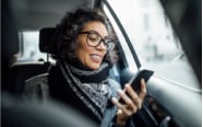 woman riding in the back seat of a vehicle checking their cellphone