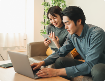 Couple sitting on couch using a laptop.