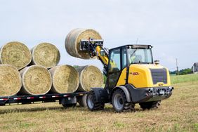 The New Holland ML50T small articulated loader placing hay bales on a trailer