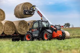 Bobcat's TL623 telehandler loading a bale of hay onto a trailer.