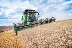 A John Deere T6 800 combine harvesting on a sloped field. 