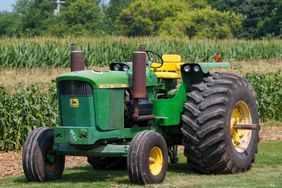 John Deere 5020 tractor parked outside of a corn field.