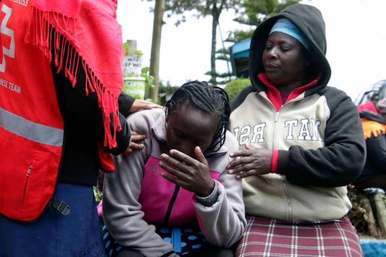 Kenya Red Cross personnel and relatives try to comfort a woman reacting near a burned-out dormitory