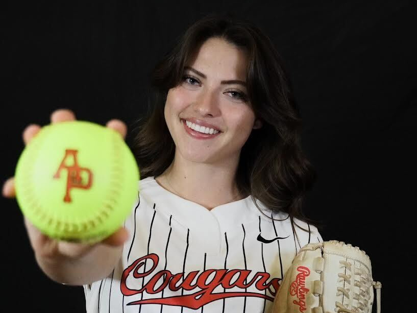 Delaney Raetz holding a softball while wearing her softball uniform.