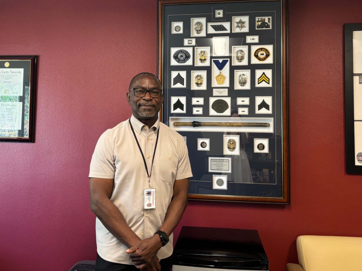 Paul Dennis stands in front of his medals in his office