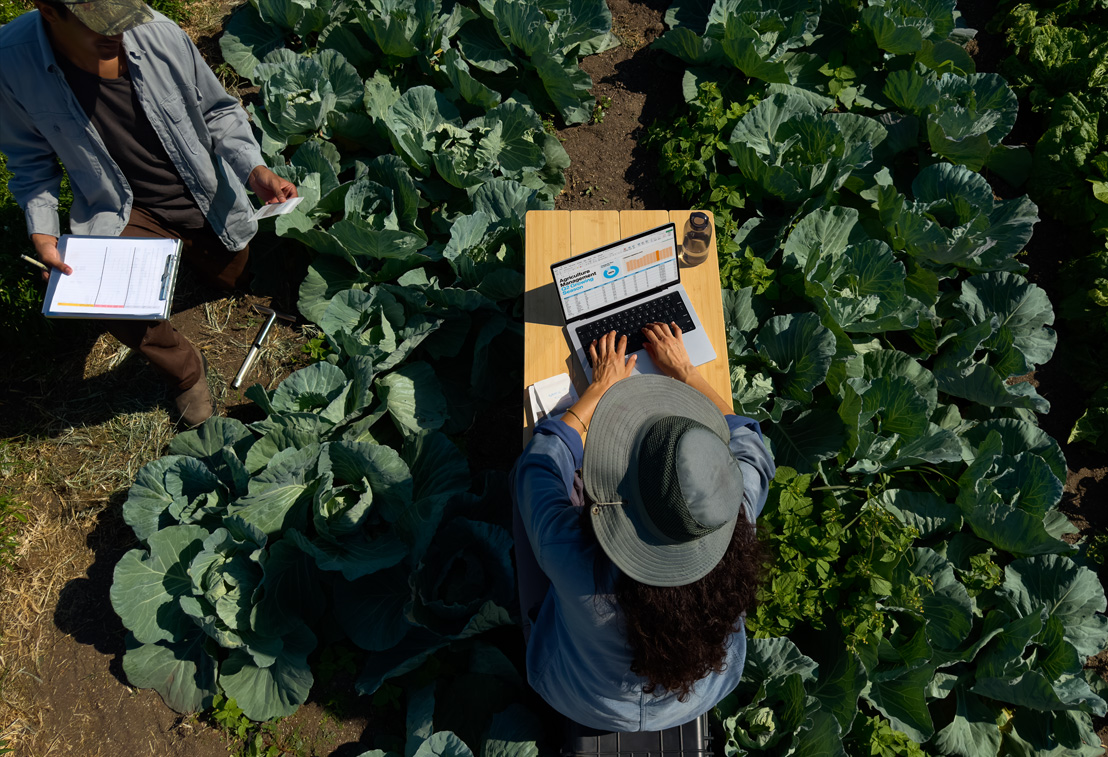 Una persona sentada al aire libre usa una MacBook Pro configurada con pantalla de vidrio nanotexturizado, donde se aprecia la reducción del reflejo.