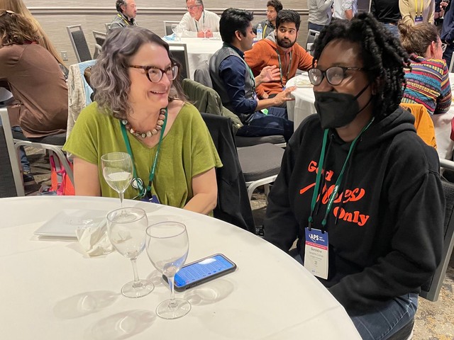 A student and a physicist sitting together at a table at APS March Meeting