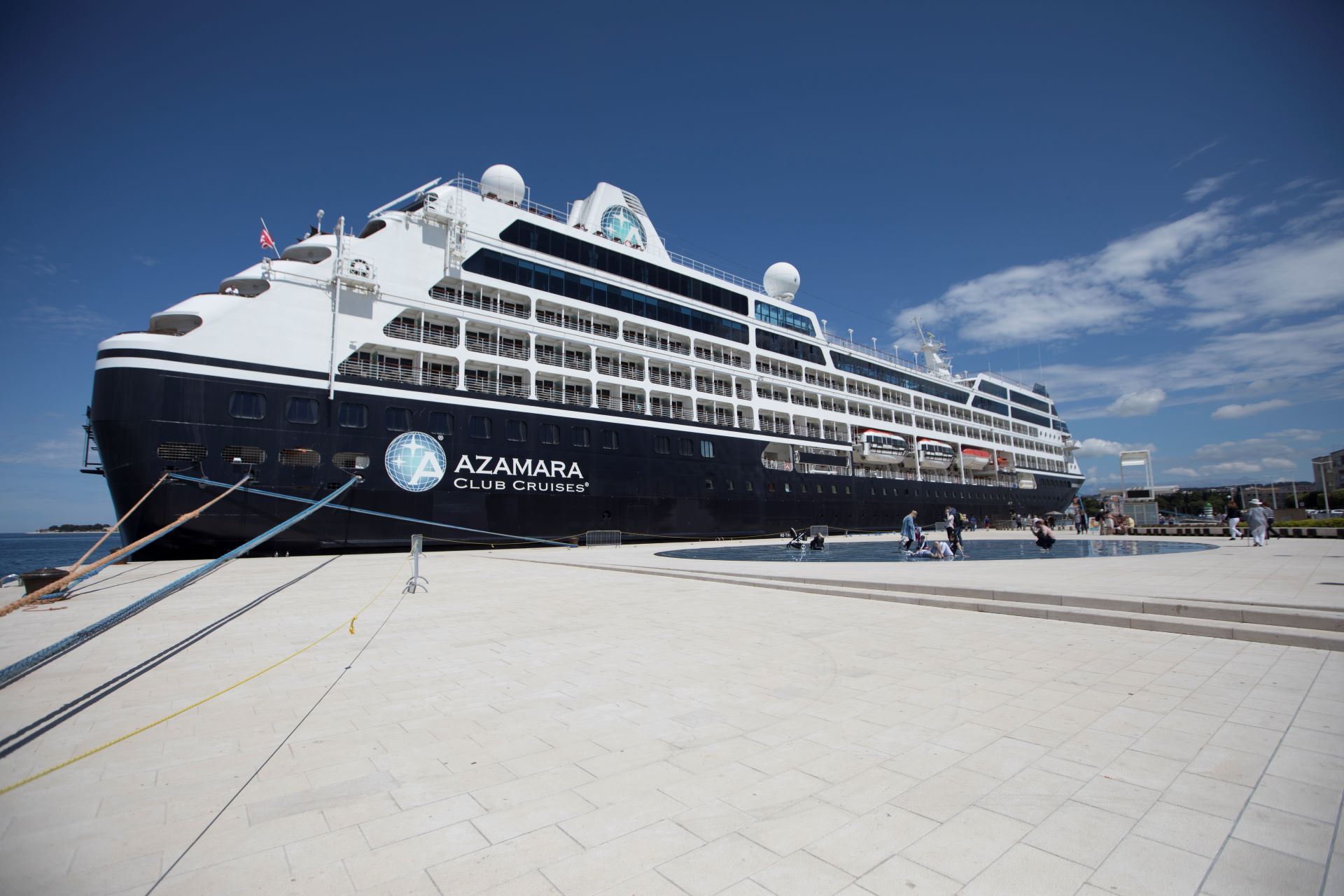 Azamara ship docked at a harbor, welcoming guests.