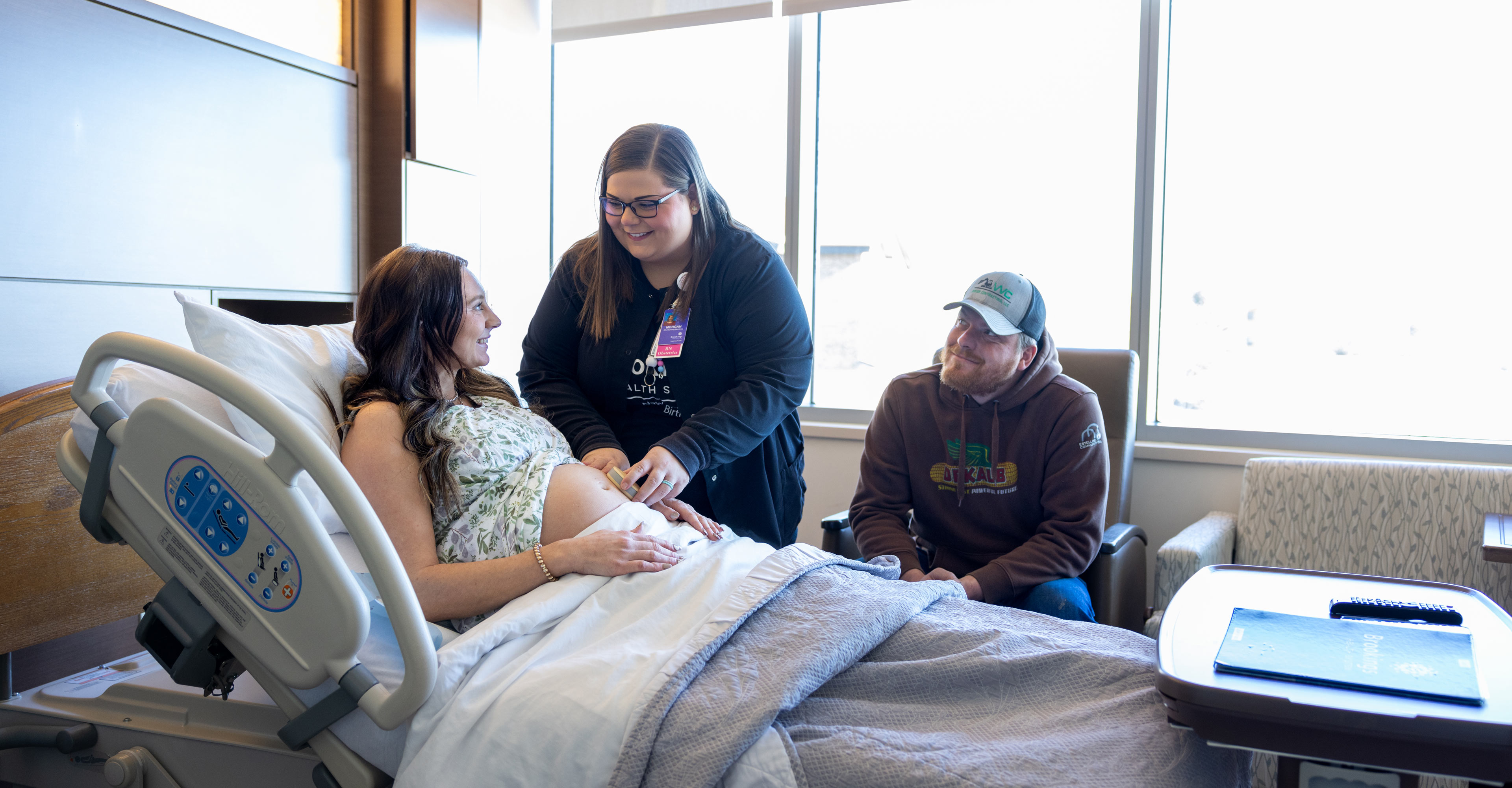 Obstetrics nurse attending to a pregnant mother in bed while dad looks on