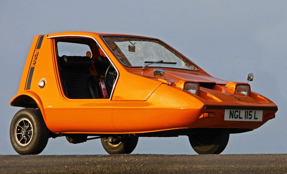 Orange three-wheeled car parked.