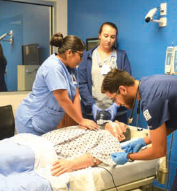 Chris Mendoza assisting in mannequin nursing exercise